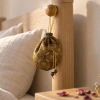 Singular Rose · Carried — by the bed Herbal sachet in a patterned silk pouch hanging from a wooden bedpost beside a linen pillow