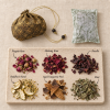 Singular Rose · Carried — what is inside Herbal sachet pouch and inner pouch above six labeled botanicals on a stone tray