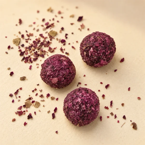 Singular Rose · Heated — pellet texture Close-up of three rose incense pellets coated in crushed rose petals, petal flakes scattered around