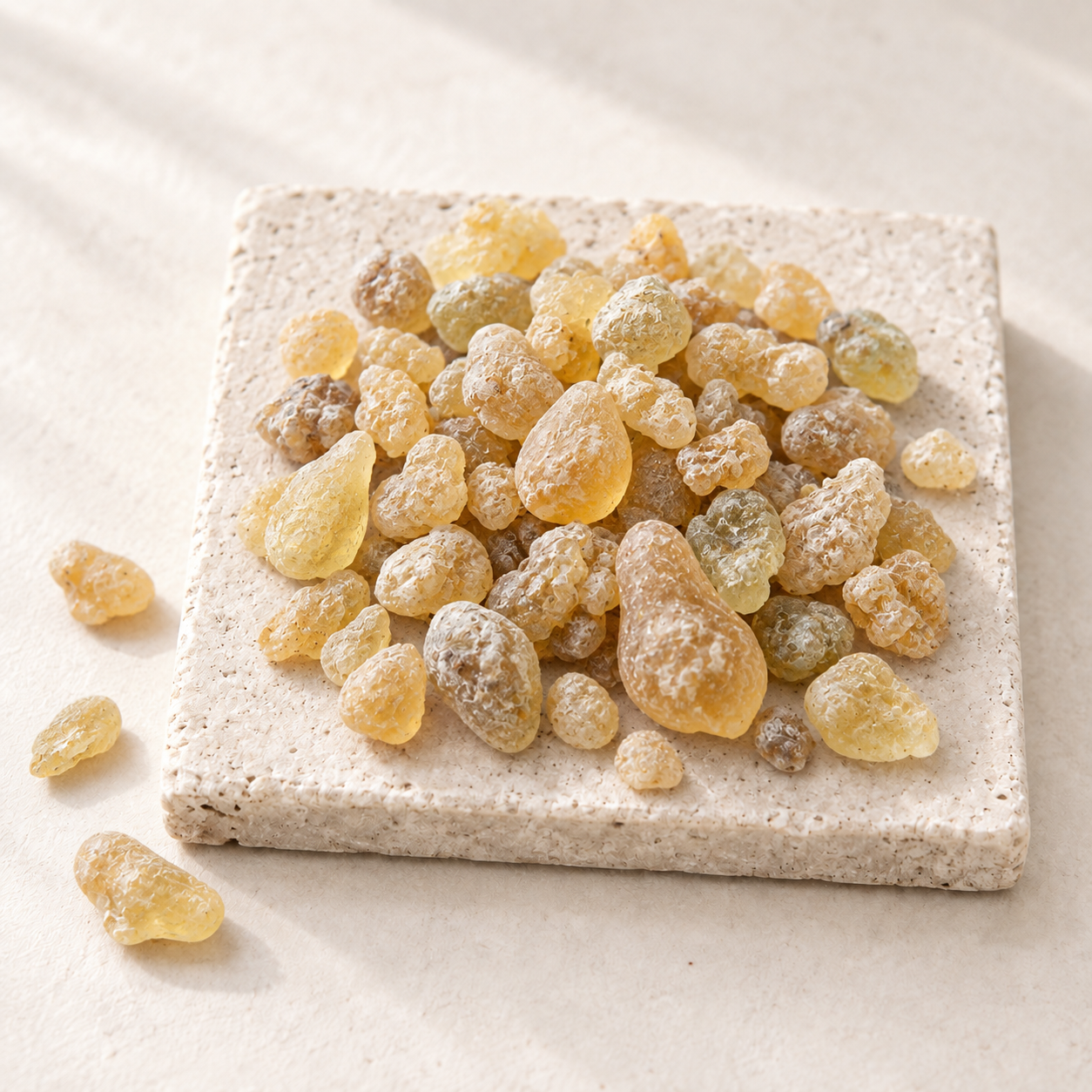 Pale golden frankincense resin tears piled on a speckled stoneware plate
