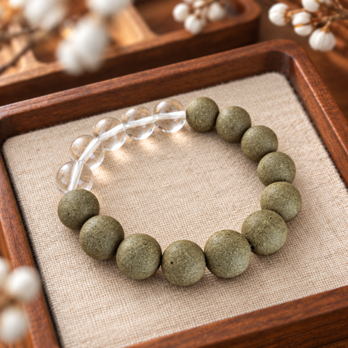 Green Hour · Worn No.1 — on a wooden tray Olive-green incense bead bracelet with a run of five clear quartz beads on a linen-lined wooden tray
