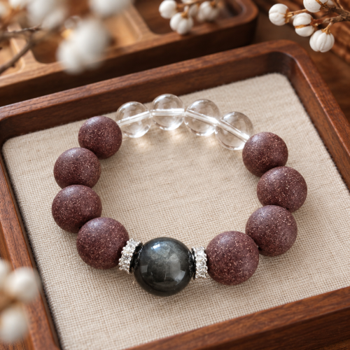 Singular Rose · Worn No.1 — on a wooden tray Rose incense bead bracelet with clear quartz, a cat's-eye obsidian bead and silver spacers on a wooden tray