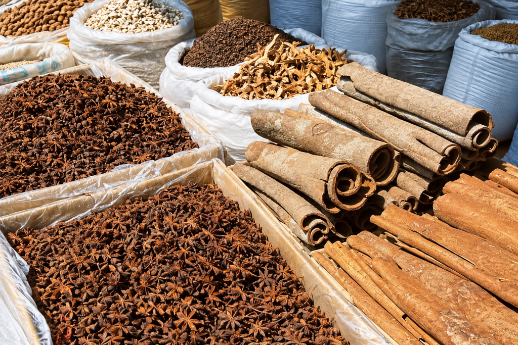 Star anise, rolled cinnamon bark and dried peel in open sacks at a sunlit spice market